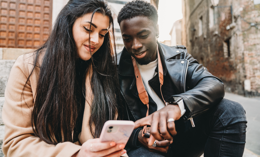 Junge Frau und junger Mann schauen auf Smartphone