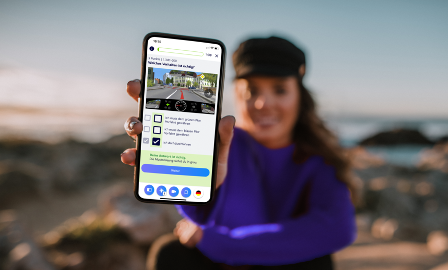 Junge Frau im Hintergrund hält Smartphone mit Führerschein Lern App nach vorne
